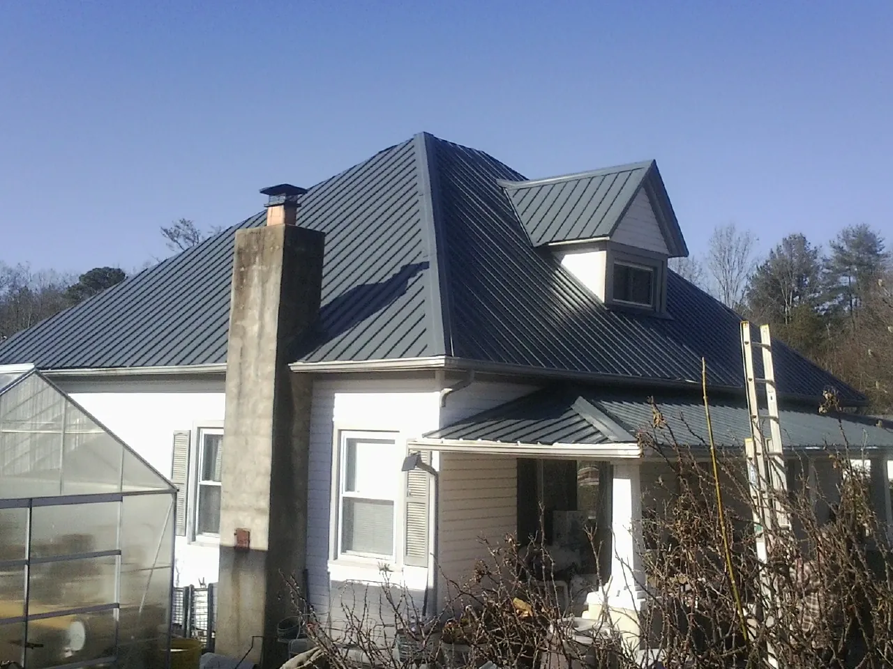 Dark blue standing seam metal roof on a white farmhouse with dormer — Slate & Tile Roof Repair by Roofing Brothers in Peachtree City