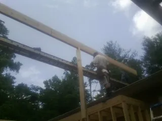 Carpenter setting a ridge beam over a new addition frame — Ice Dam Removal by Roofing Brothers in Peachtree City