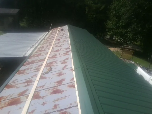 Old rusted panels beside newly installed green metal roofing — Wind Damage Roof Repair by Roofing Brothers in Peachtree City