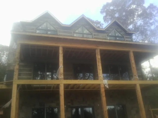 Dormers and porch framing on a large log home under construction — Roof Coating work by our crew in Peachtree City