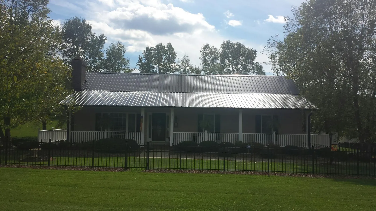 Gray metal roof on a brick ranch with a full width front porch — Gutter Guard Installation work by our crew in Peachtree City