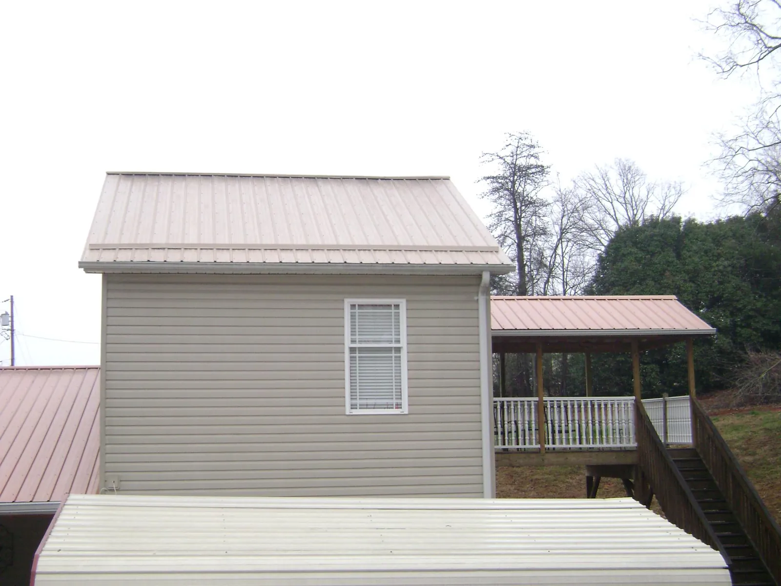 Tan metal roofs on a two story addition and attached porch, from a Roof Replacement job in Peachtree City