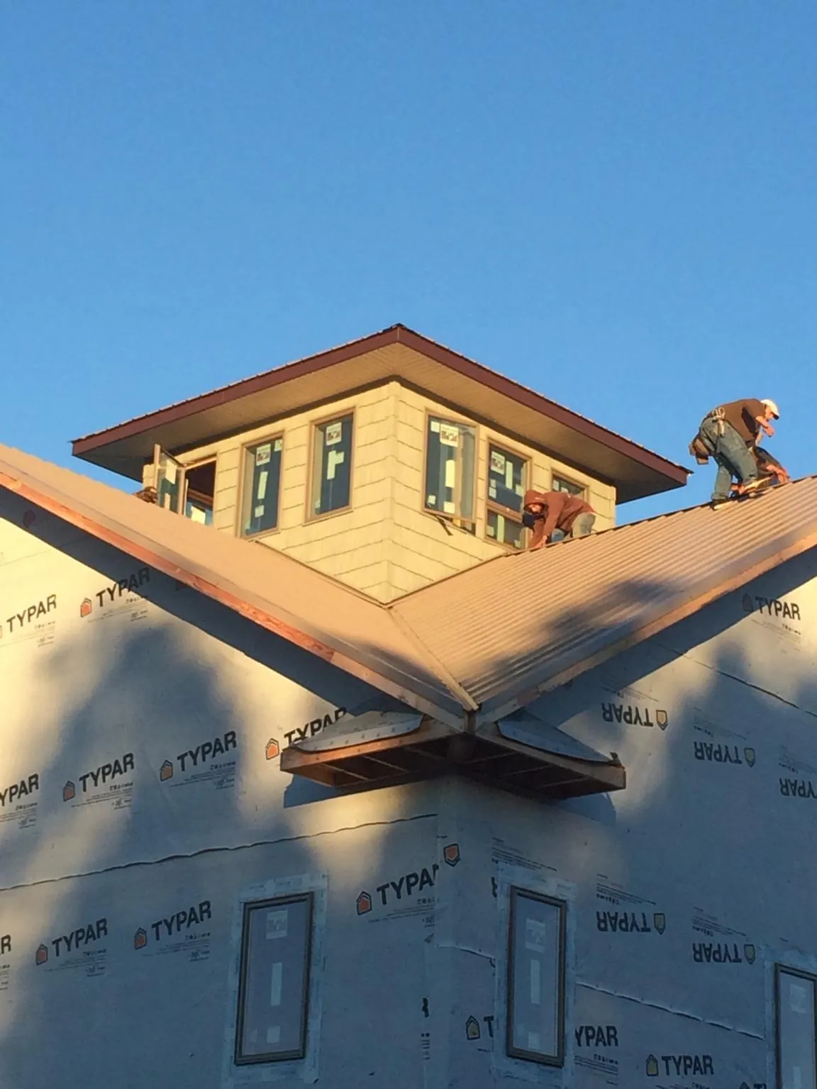 Roofers working around a rooftop cupola on a new metal roof at sunset — Roof Waterproofing in Peachtree City by Roofing Brothers